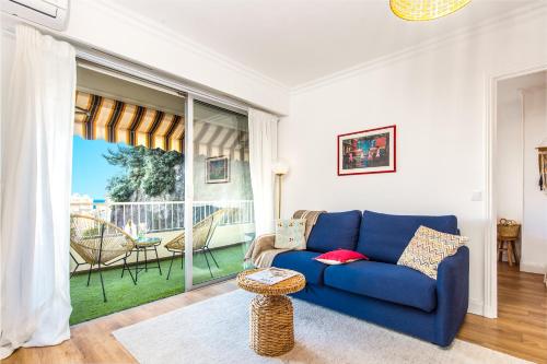 un salon avec un canapé bleu et une grande fenêtre dans l'établissement 5mn Monaco - Cosy 2 pièces - Balcon vue mer - CL, à Beausoleil