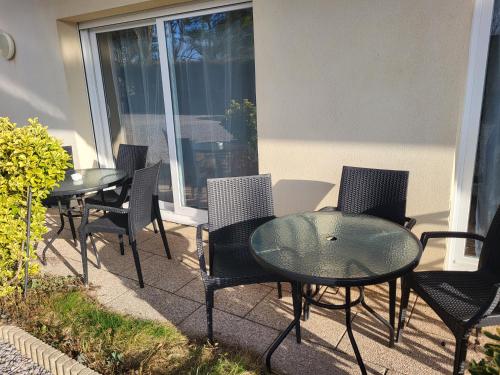 a patio with two tables and chairs and a window at La marine D'opale in Ambleteuse