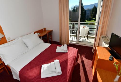 a hotel room with a bed and a television and a balcony at Hotel Alkar in Sinj