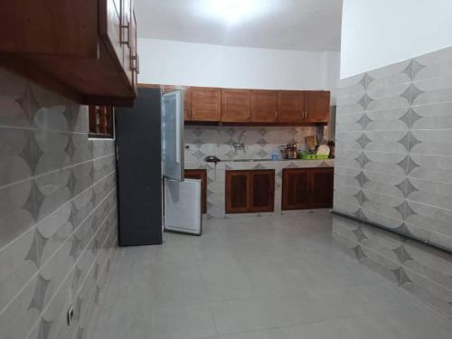 a kitchen with wooden cabinets and a refrigerator at Lumineuse loge privée de 4 chambres en air de plage in Cotonou