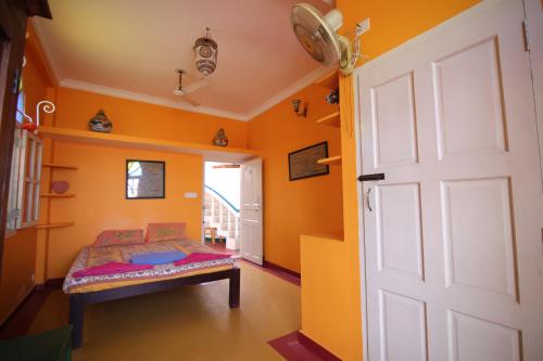 a bedroom with orange walls and a door at Holi-Wood Guesthouse in Puducherry