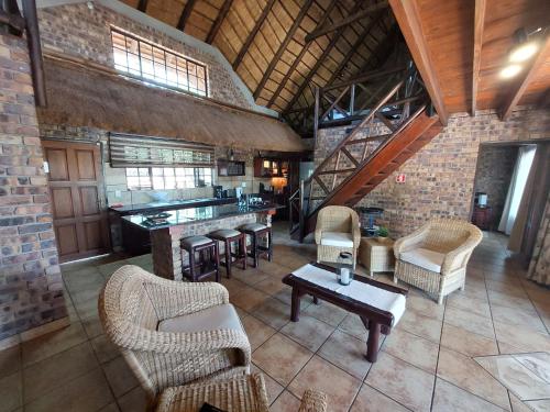 a living room with chairs and a table and a kitchen at Khumbula iAfrica 1 in Marloth Park