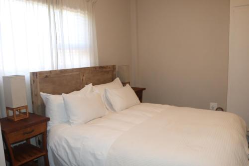 a bedroom with a bed with white sheets and a window at du Repos (Lovely & Relaxing 2-Bedroom Unit with Patio) in Springbok