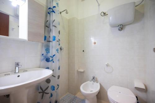 a white bathroom with a sink and a toilet at Villaggio Camping Fiorina in Capo Vaticano