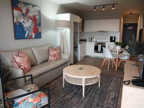 a living room with a couch and a table and a kitchen at 302 Mossel Cove Sea View Deluxe in Mossel Bay