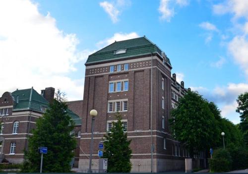 a large brick building with a green roof at Forenom Hotel Apartments Geijersgatan - City Center in Gothenburg