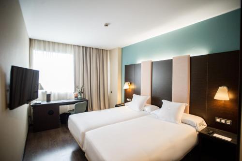 a hotel room with two beds and a television at AZZ Pamplona Norte Hotel in Pamplona