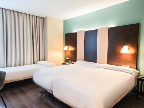 a hotel room with two beds and a window at AZZ Pamplona Norte Hotel in Pamplona