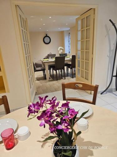 un vase de fleurs violettes posé sur une table dans l'établissement La Gilleraie gîte de campagne proche du Puy duFou, à Le Boupère