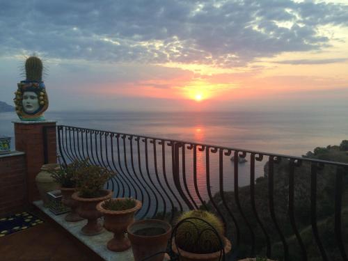 a view of the sunset from a balcony with plants at B&B Martina in Taormina