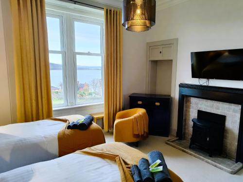a hotel room with two beds and a fireplace at Bella Vista Manor - with elevated views over Rothesay & Loch Striven in Rothesay