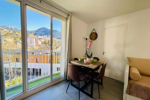 une pièce avec une table et une grande fenêtre dans l'établissement Charming T3 with balcony in the heart of Briançon, à Briançon