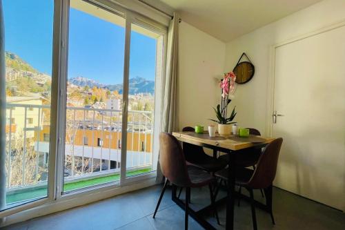 une salle à manger avec une table et une grande fenêtre dans l'établissement Charming T3 with balcony in the heart of Briançon, à Briançon