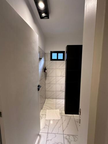 a bathroom with a shower and a white tile floor at Casagrande Hotel Boutique in Tinogasta