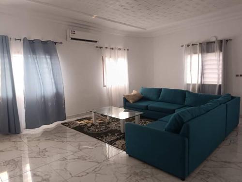 a living room with a blue couch and a table at Lumineuse loge privée de 4 chambres en air de plage in Cotonou