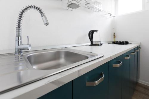 una cucina con lavello in acciaio inossidabile e armadi blu di Studio Targoviste a Târgovişte