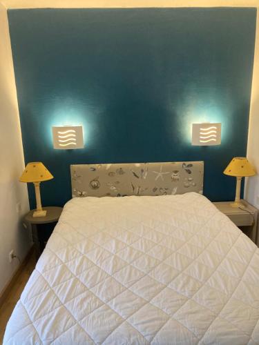 - une chambre avec un lit avec un mur bleu et deux lampes dans l'établissement Appartement 6 personnes dans résidence avec piscine, à Le Touquet-Paris-Plage