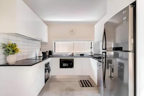 a kitchen with white cabinets and a stainless steel refrigerator at Granny Guest House Sydney Blue Mountain in Kingswood