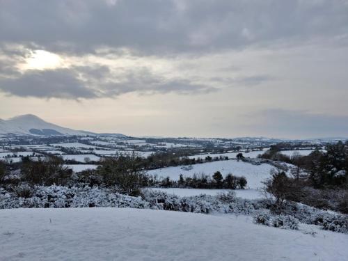 a snow covered hill with a view of a valley at Riverside cabin in Limerick