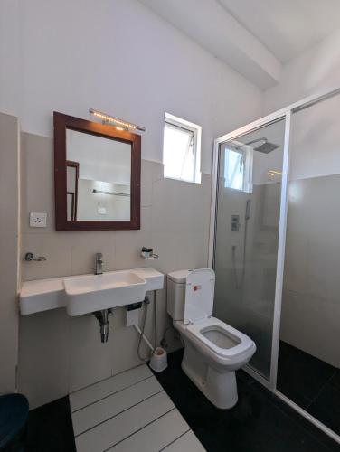 a bathroom with a toilet and a sink and a mirror at Bliss Apartment Hikkaduwa in Hikkaduwa