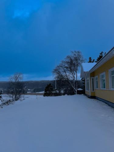 a house covered in snow next to a house at Keltainen talo - tilava huvila lähellä Saloa in Vartsala