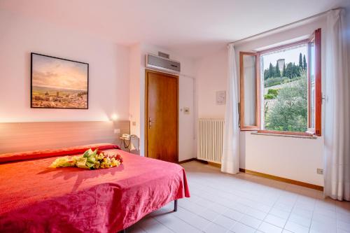 una camera con letto rosso e finestra di Hotel San Rufino ad Assisi