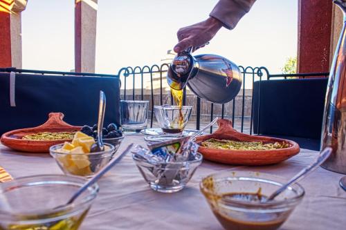 a person pouring food into bowls on a table at lmtounipalace in Ouarzazate