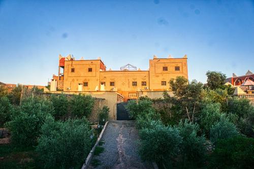 a large brick building in the background with bushes at lmtounipalace in Ouarzazate