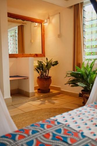 a bedroom with a mirror and a potted plant at Salty's Kitesurf Village in Kilifi