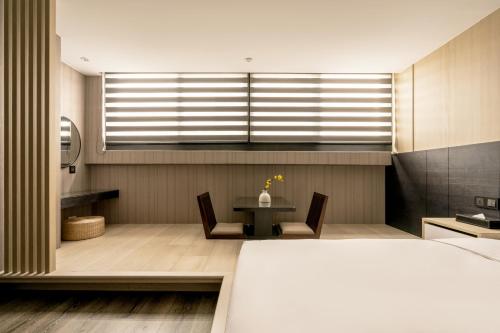 a bedroom with a bed and a table and a window at suye hotel in Taichung