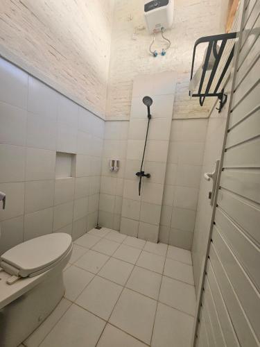 a white bathroom with a toilet and a shower at Pasir Putih resort & Cafe in Maluk