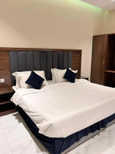 a bedroom with a large white bed with blue pillows at شاليهات سرايا ان لبيوت العطلات in Jazan
