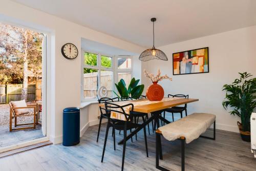 a dining room with a table and chairs and a clock at 5 Bed House Sleeps 9 Parking Garden Pet Friendly in Sileby in Sileby