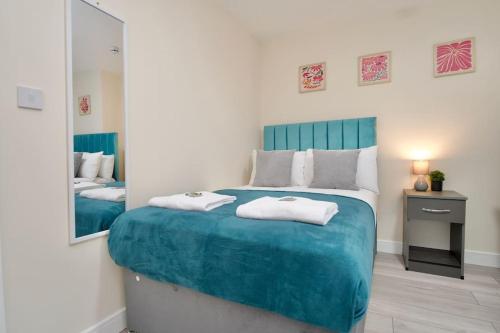 a bedroom with a large blue bed with a mirror at Cosy 1Bed Flat with Garden, Parking & Free Netflix in Coventry