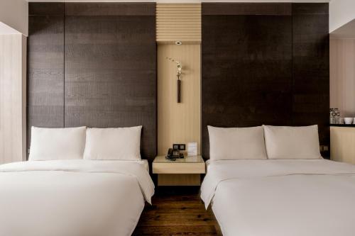 two beds sitting next to each other in a room at suye hotel in Taichung