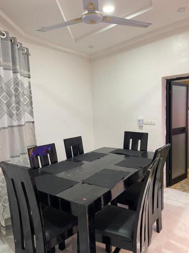 a black dining room table with chairs and a ceiling fan at Tkj in Adidomé