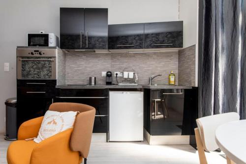 une cuisine avec des armoires noires et une chaise orange dans l'établissement Beau duplex, proche zénith et palais des sports, à Caen