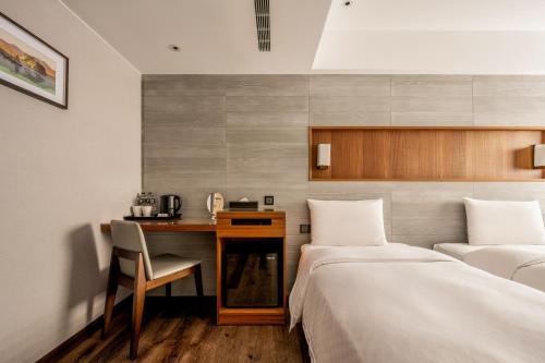 a hotel room with two beds and a desk at suye hotel in Taichung