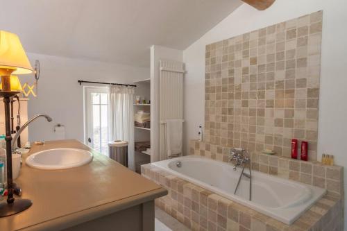 a bathroom with a large tub and a sink at Les Beaumettes, villa provençale à deux pas de Gordes in Beaumettes