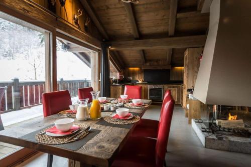 une salle à manger avec une table, des chaises et une cheminée dans l'établissement Chalet l'Ourson, avec jacuzzi, sauna, services hôteliers, à Chamonix-Mont-Blanc