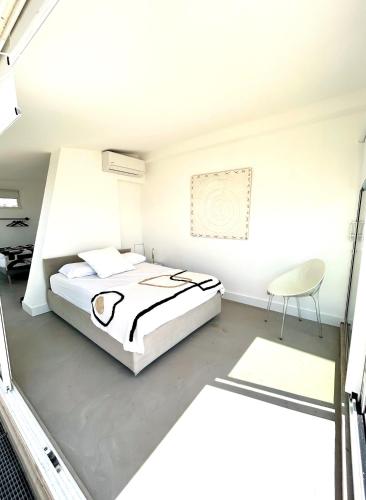 une chambre blanche avec un lit et une chaise dans l'établissement Riviera rooftop - front de mer avec terrasse dans le centre, à Antibes