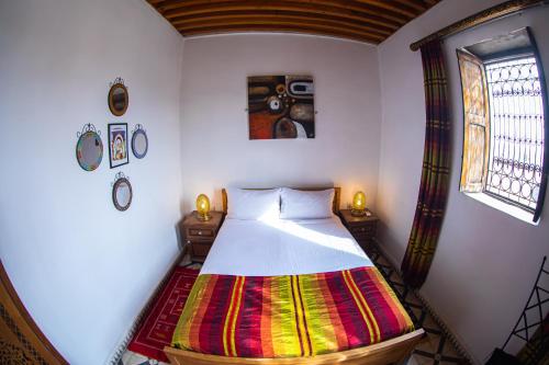 a bedroom with a bed with a colorful blanket at Dar Fez Arinas in Fès