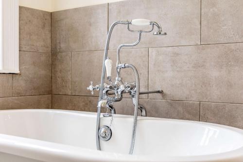 a bath tub with a shower in a bathroom at Leigh Park Country House Hotel & Vineyard, BW Signature Collection in Bradford on Avon