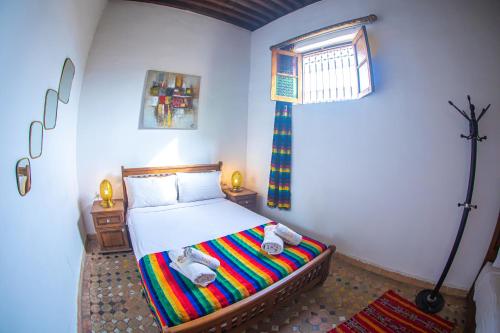 a bedroom with a bed with a colorful blanket at Dar Fez Arinas in Fès