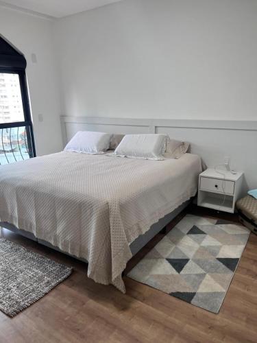 a bedroom with a white bed with a rug at Apartamento, quadra mar in Itapema