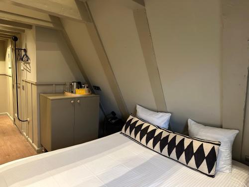 a bed with a black and white pillow on it at The Times Hotel in Amsterdam