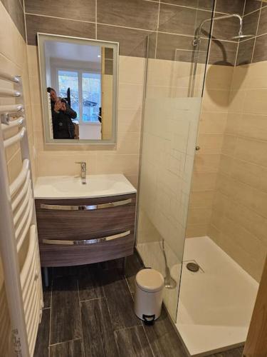 une personne prenant une photo d'une salle de bains avec lavabo et douche dans l'établissement Appartement Serre Chevalier Montgenèvre, à Briançon