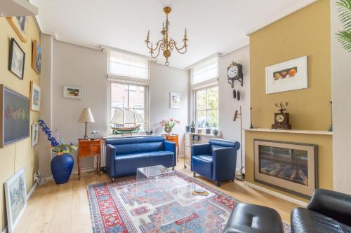 a living room with blue chairs and a fireplace at Logement Old Boorn in Borne