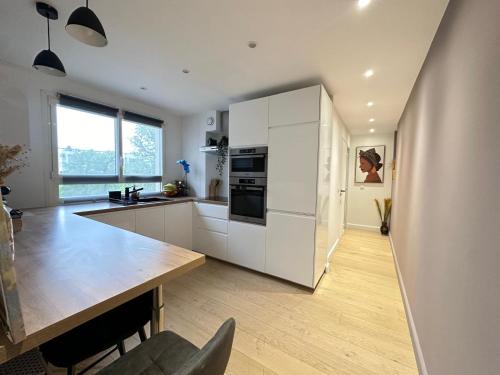 une cuisine avec des armoires blanches et une table en bois dans l'établissement Appartement Rooftop, à Montmorency