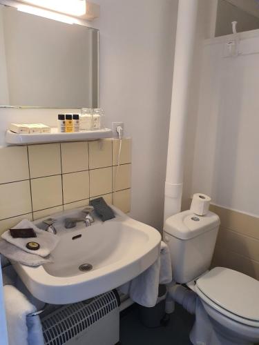 une salle de bain avec un lavabo blanc et des toilettes dans l'établissement Hôtel de la promenade, à Bains-les-Bains